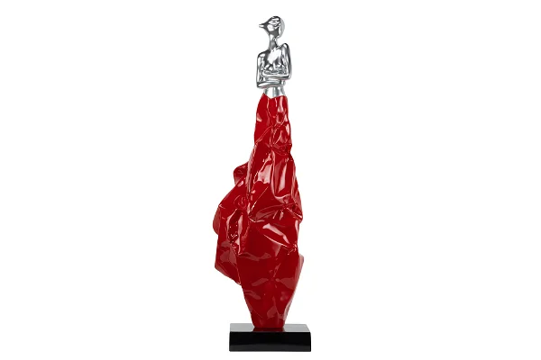 Red elongated sculpture, silver figurine on top, contemporary art.