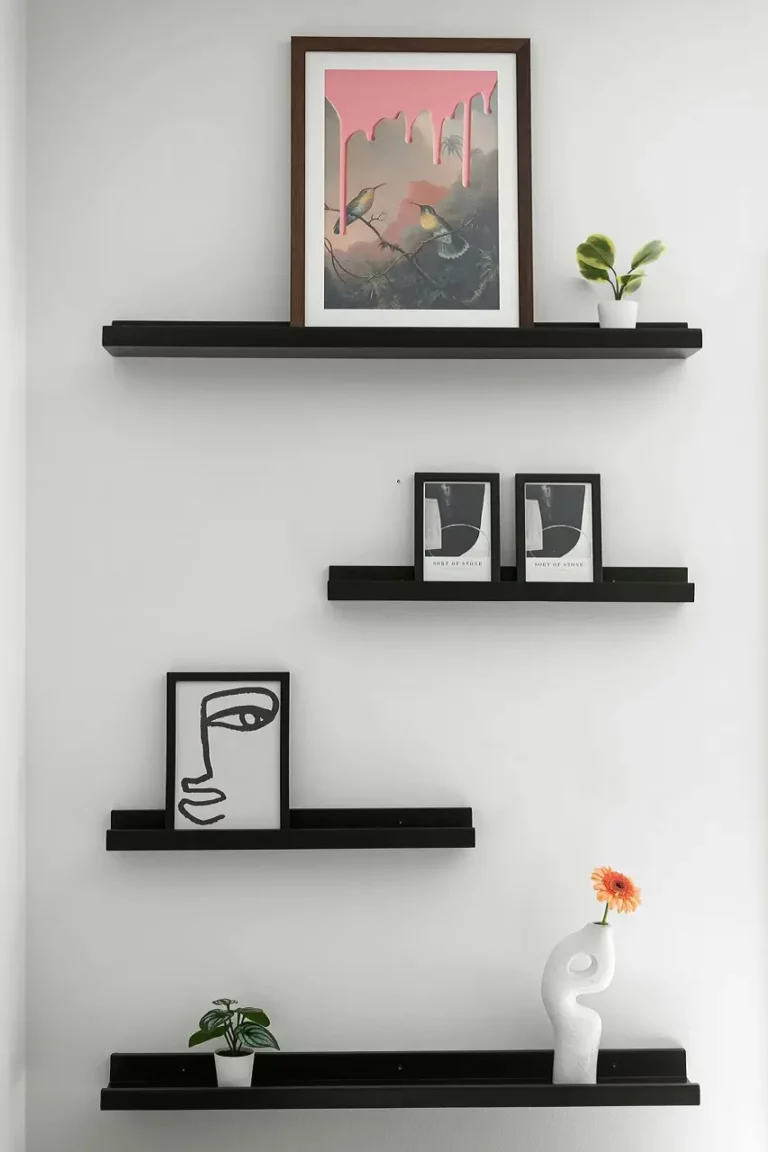 Estantería flotante con cuadros enmarcados en la pared como ideas creativas para colgar Cuadros