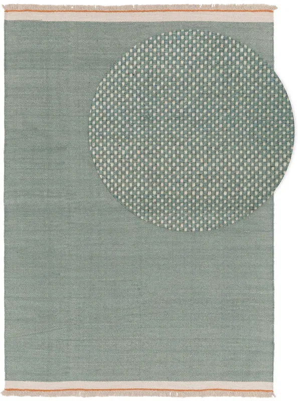Soft mint green rug with a woven circular pattern on one corner, featuring a minimalist design with fringe edges.