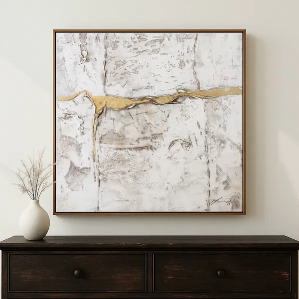 An abstract artwork in white, gold, and gray hangs above a corner table topped with a white vase.